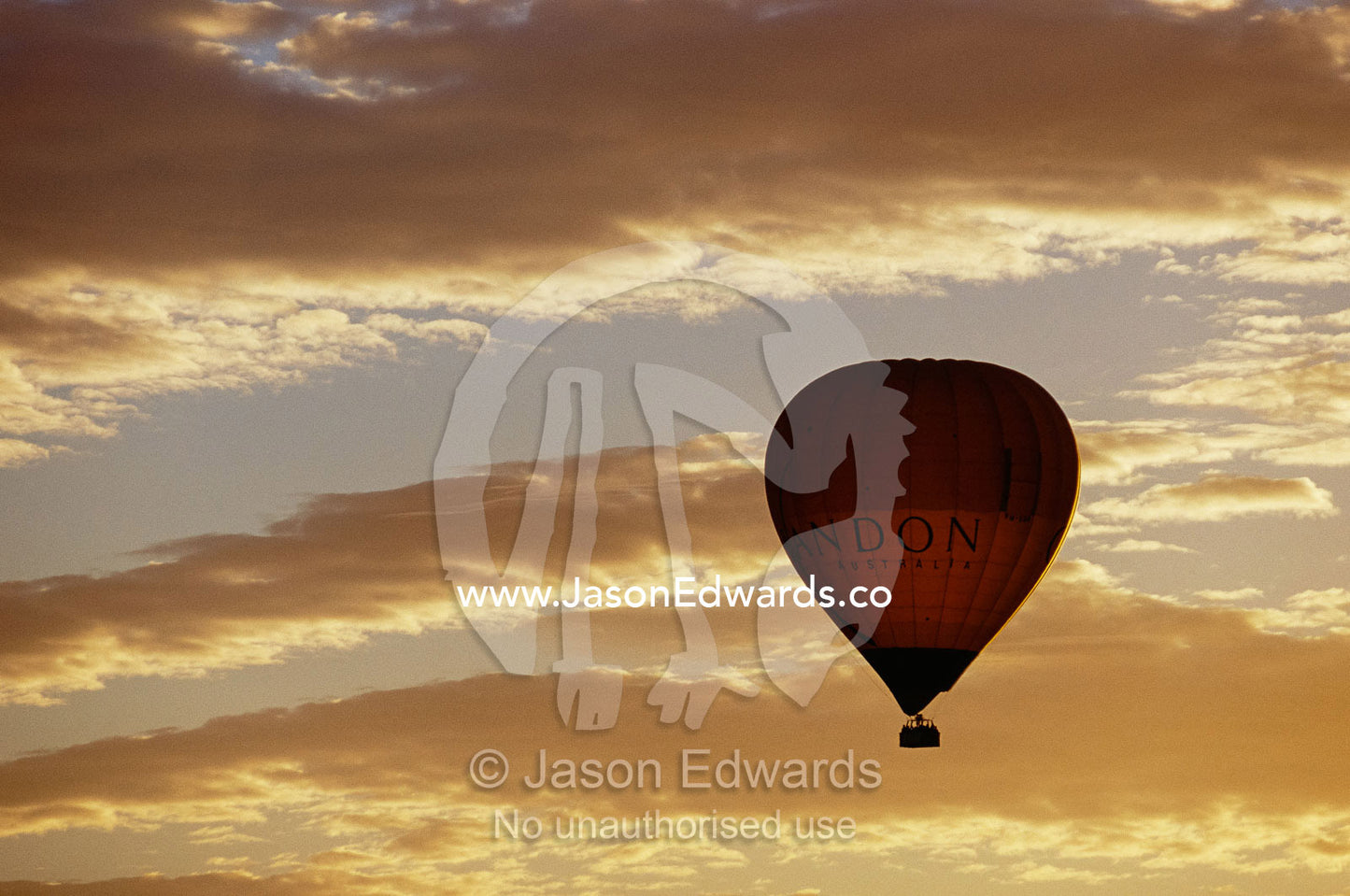 A soaring hot air balloon against a cloud-filled sky at dawn. Yarra Valley, Victoria, Australia.