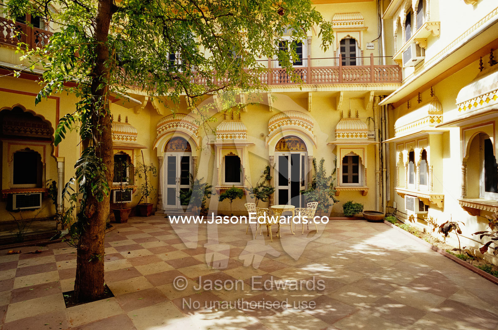 Table and chairs in the courtyard of a yellow building. Jaipur, India.