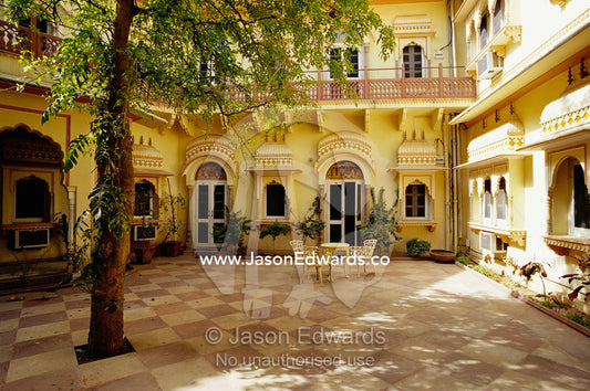 Table and chairs in the courtyard of a yellow building. Jaipur, India.