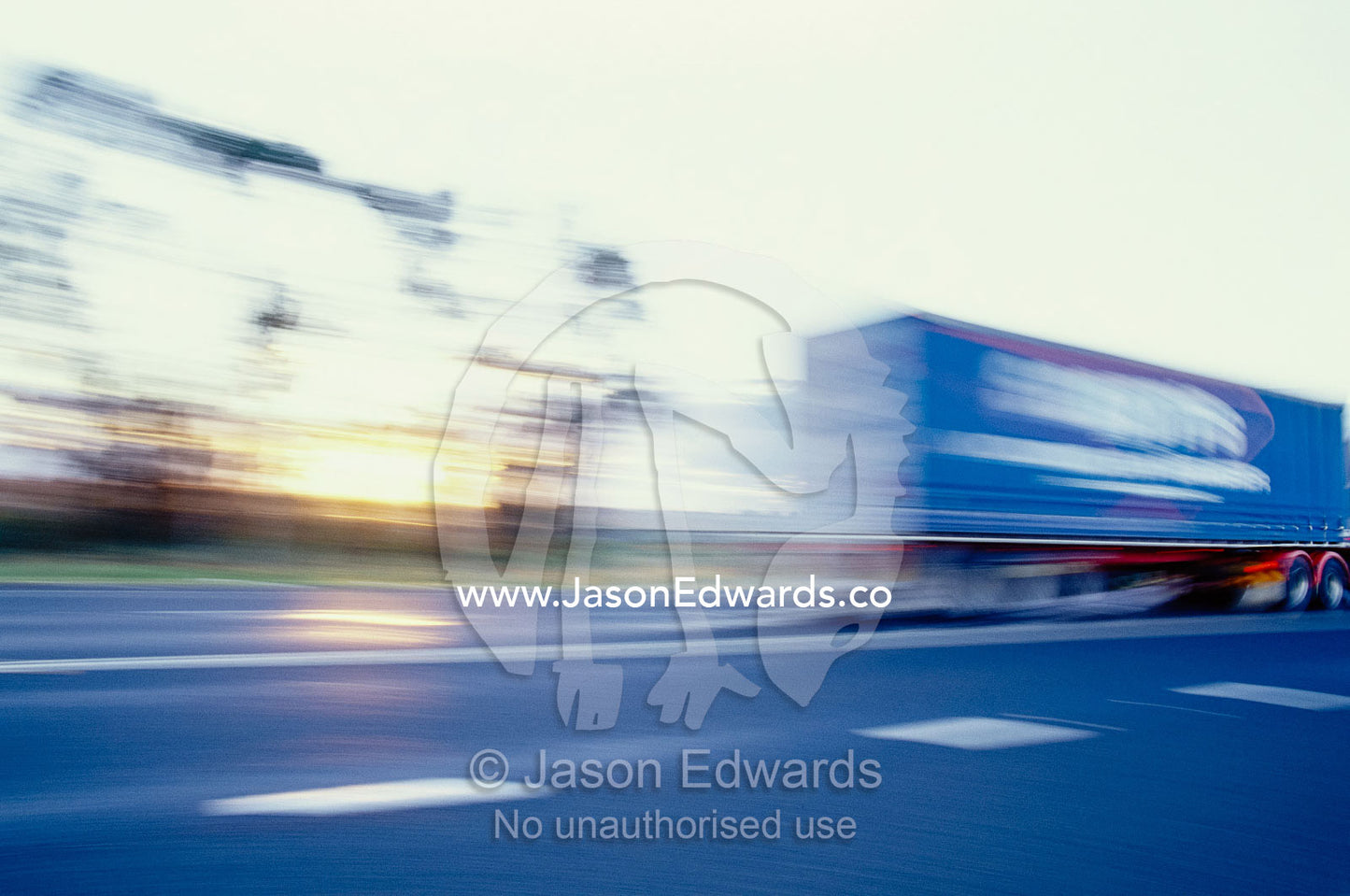 A tractor trailer speeding down a highway at sunset. Narrabri, New South Wales, Australia.