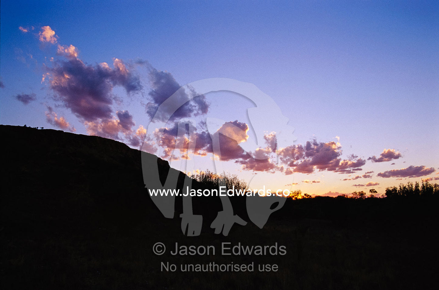 Storm cloud reflecting sunset light over a desert. West Macdonnell National Park, Northern Territory, Australia.