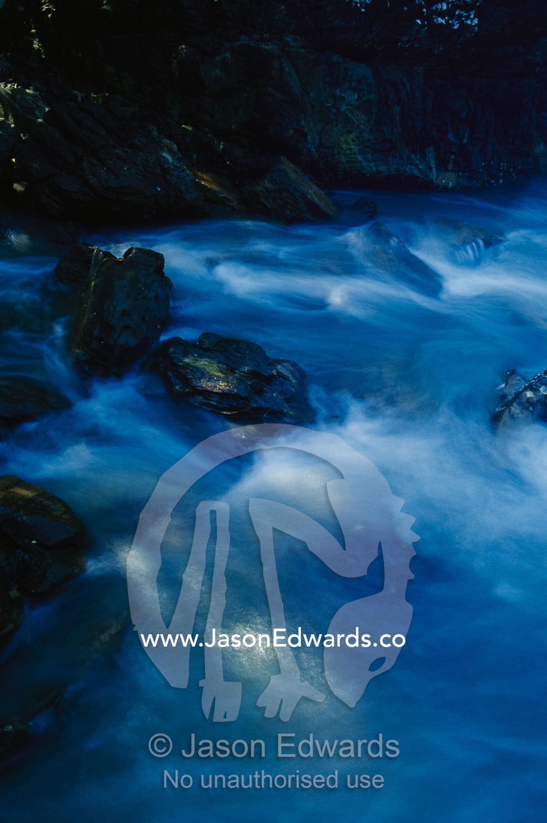 Blue pastel water breaks over rocks at Bittangabee Bay. New South Wales, Australia.