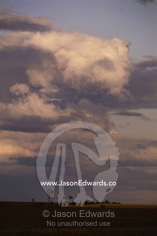 Windmill and plains under stormy sky. Emerald, Queensland, Australia.