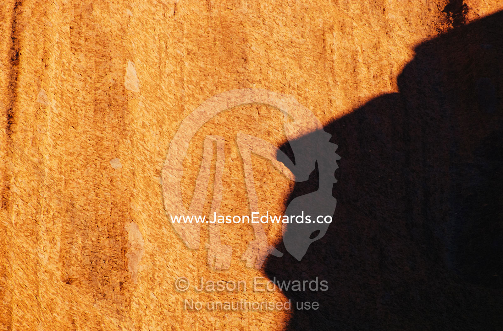 A human-like shadow cast by a rock formation onto another large rock. Uluru National Park, Northern Territory, Australia.