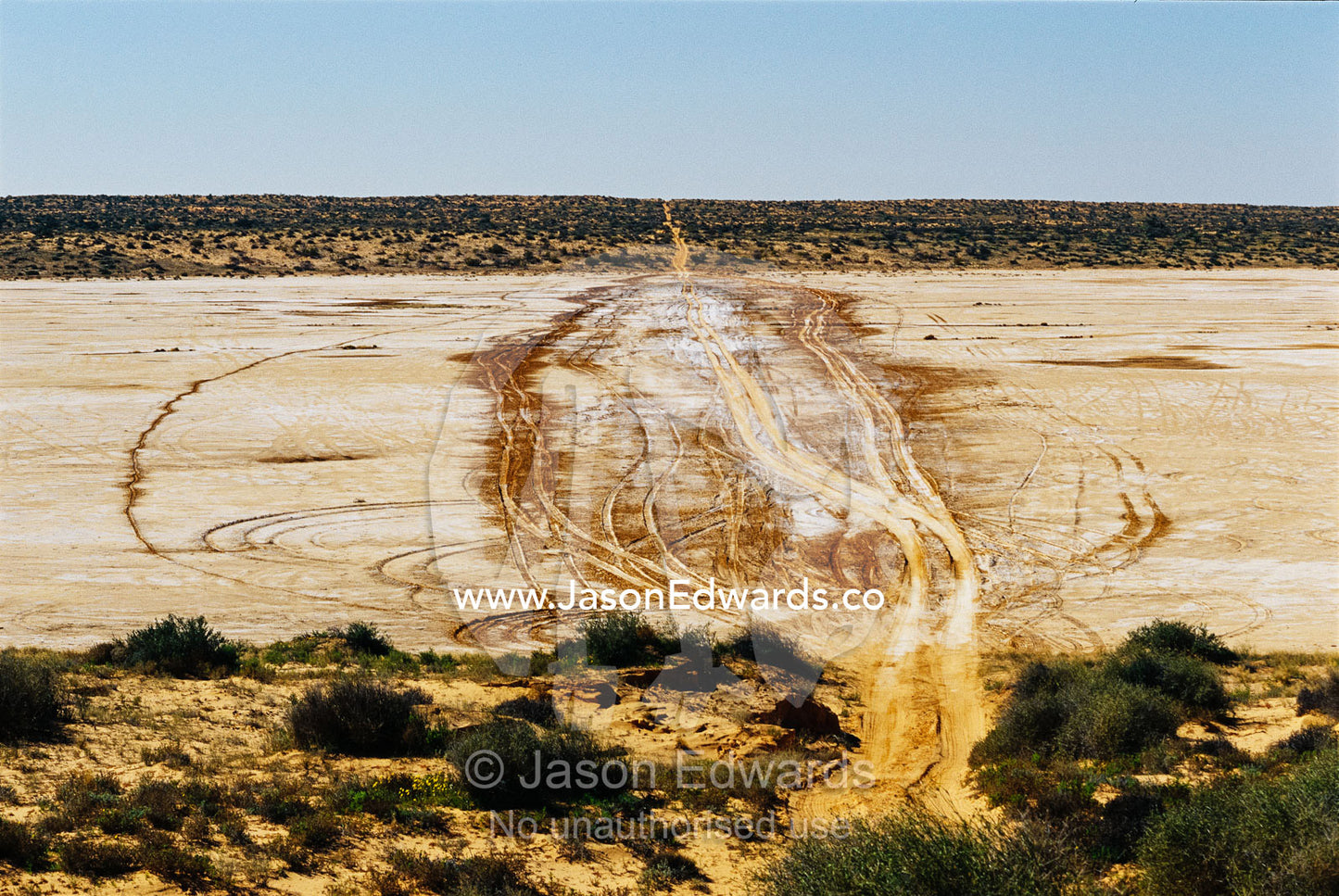 Destructive 4WD tracks on a clay pan between parallel sand dunes. Simpson Desert Conservation Park, South Australia.
