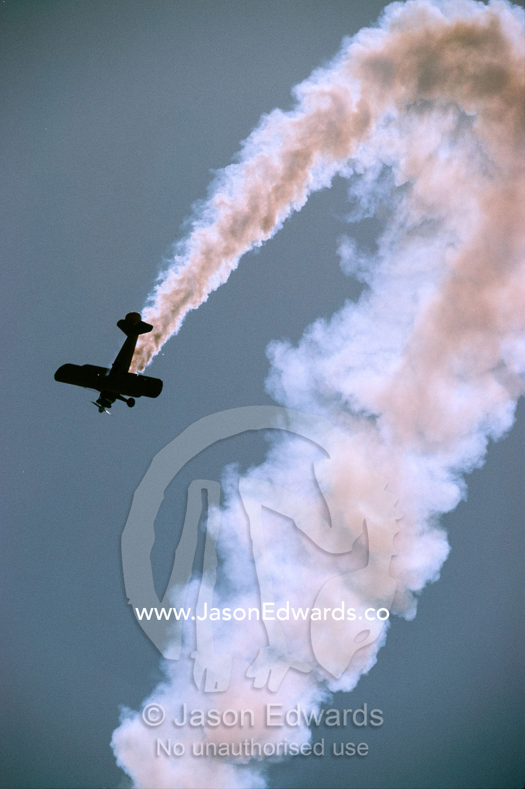 A stunt bi-plane in a steep dive trails smoke at the Avalon Airshow. Victoria, Australia.