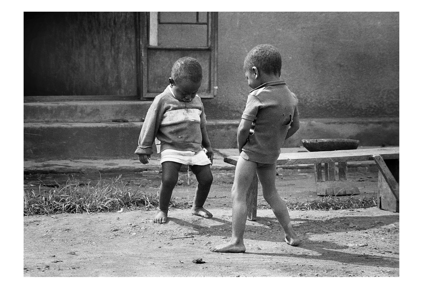 Two young boys playing in the street urinate at each other in fun. Kabale, Western Uganda.