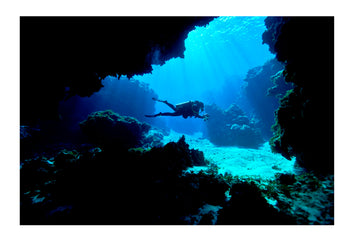 A scuba diver exploring an underwater cave in a tropical coral reef. Kokod Point, Ringgold Isles Archipelago, Pacific Ocean, Fiji Islands.