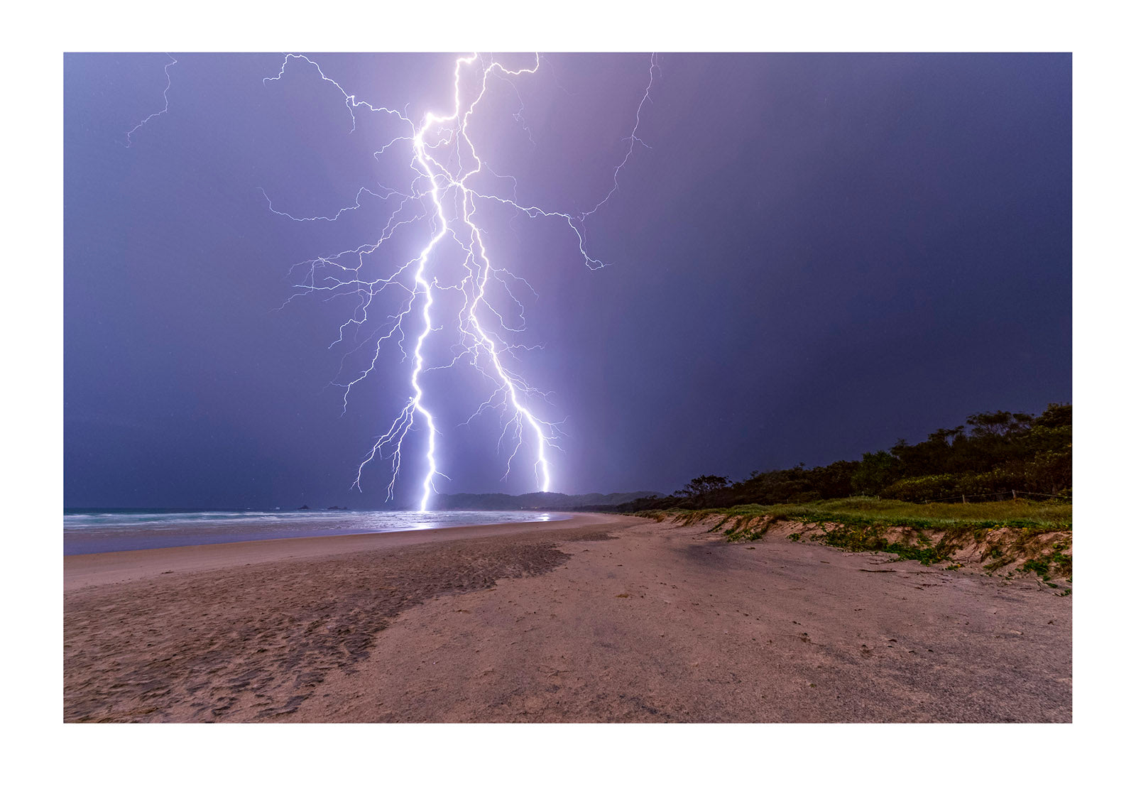 Lightning strikes a sand dune and the ocean during an electrical storm. Suffolk Park, New South Wales, Australia.