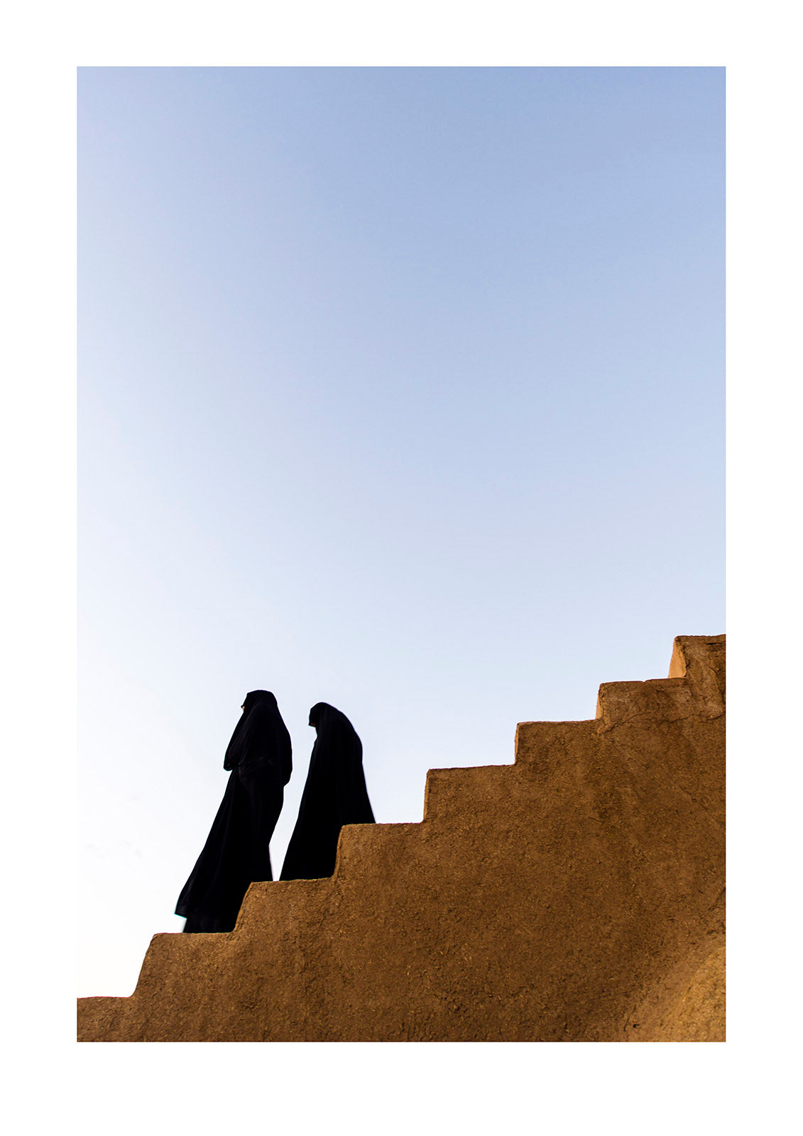 Women dressed in chador descend the stairs of an ancient fortress. Narin Castle, Meybod, Meybod County, Yazd Province, Islamic Republic of Iran.