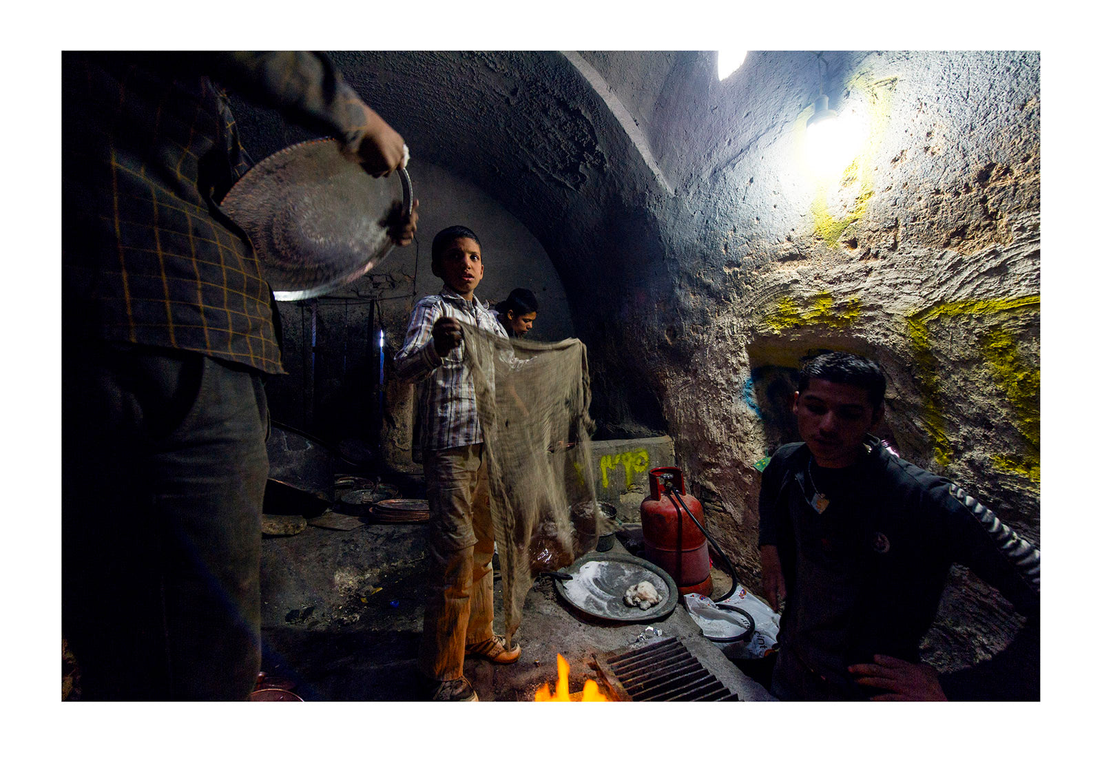 Teenage boy labourers heating and polishing copper and silver platters and pots in a workshop in a bazaar. Yazd, Yazd Province, Islamic Republic of Iran.