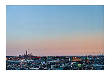 Factory chimneys rise above the flat city skyline of Copenhagen at sunset. Copenhagen, Denmark.