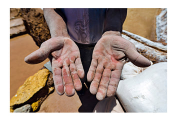 The hands of a laborer working the terraced pond walls in an ancient Inca salt mine. Maras, Peru.