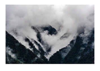 Storm clouds engulf the steep forested slopes and jagged mountain peaks of the Andes. Peru.