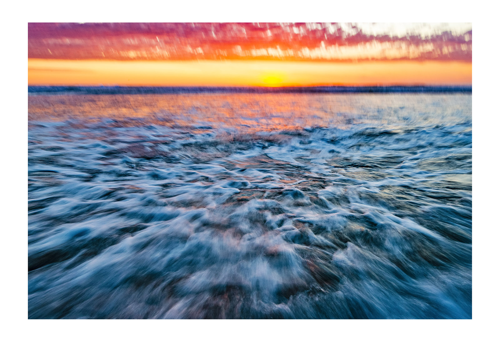 The blur of waves rushing onto a beach on an incoming tide at sunset. Venus Bay, Victoria, Australia.