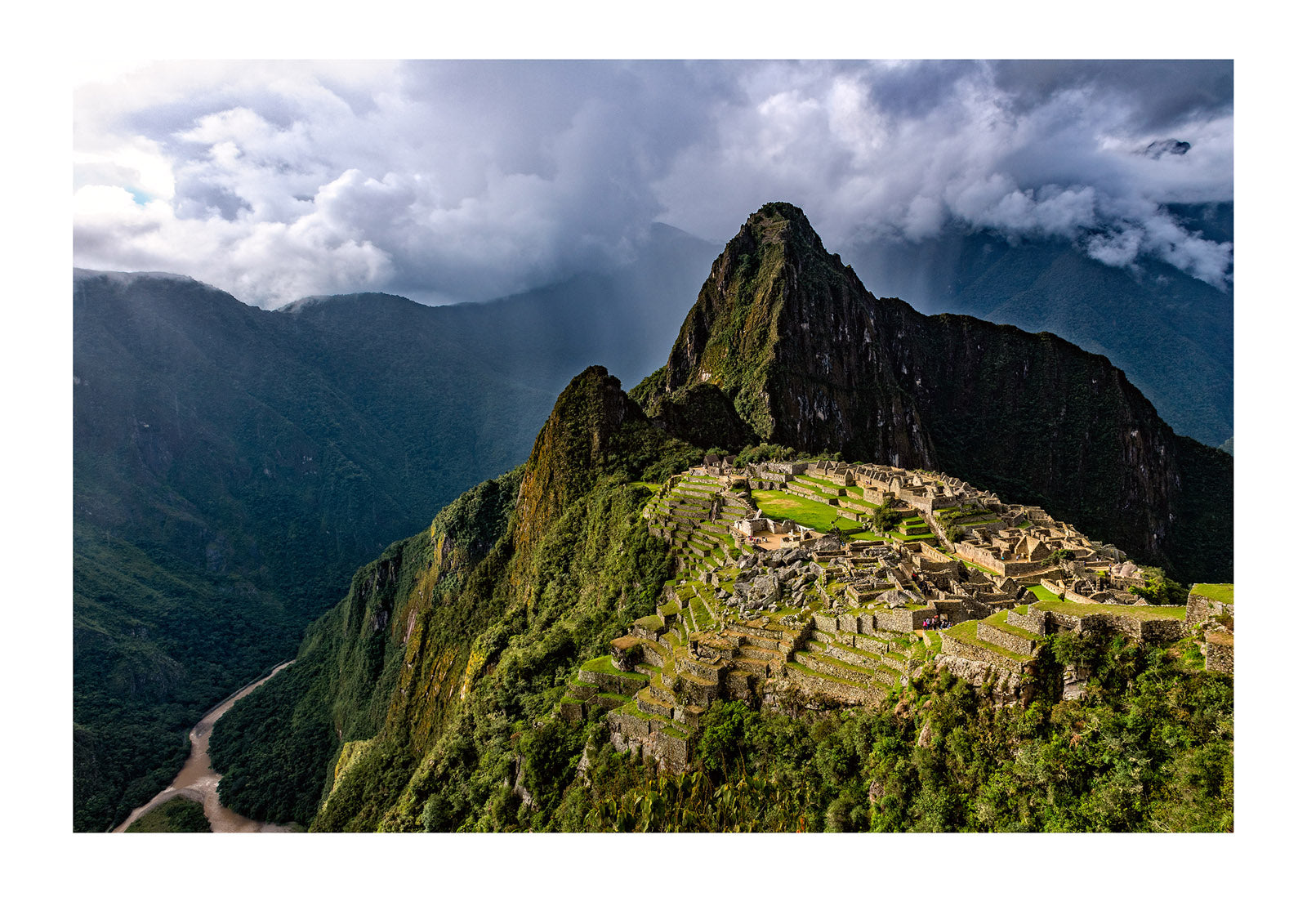 Machu Picchu. On a rain and mist filled day I decided to gamble my last hours to see if the sun would peer through a gap in the clouds. Minutes before the gates closed, I was given a single ray that illuminated the ancient ruins.  Peru.