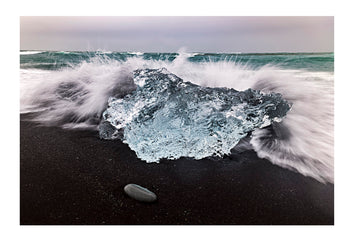 A block of clear ice fractured from an Icelandic glacier, travelled down river and into the raging sea. Wind, waves and currents returned it to shore on a black volcanic sand beach where it will be pounded back into it's raw elements, air and water.