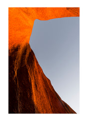The blistering oxide on the sheer face of Uluru in central Australia, glows with an internal heat in the setting sun. The ancient massive rises from the desert plains showing as many faces as there are hues in the pollution-free sky.