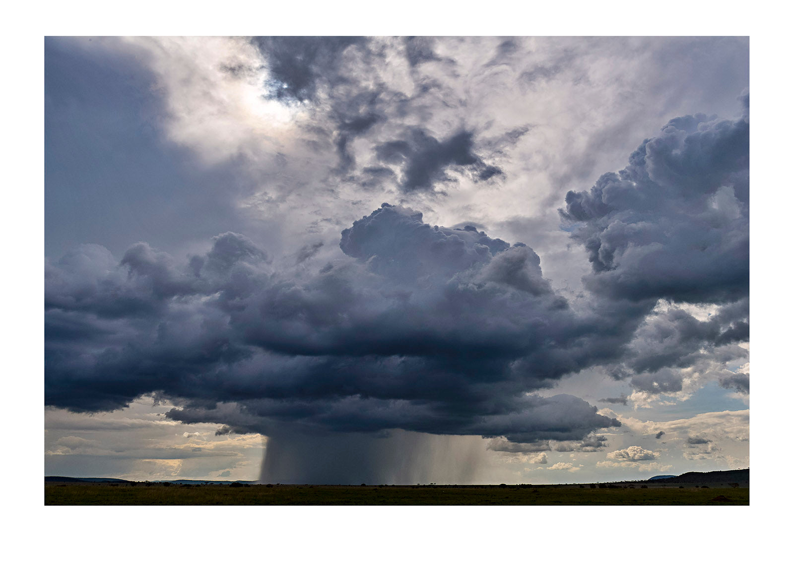 An enormous thunderhead delivers a deluge of rain over the vast savannah of the Serengeti. Serengeti National Park, Tanzania.