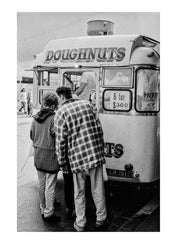 People wait to purchase hot jam-filled donuts on a cold winters day at the Queen Victoria Market, 1980's. Captured on Ilford HP5 black and white negative film. Melbourne, Victoria, Australia.