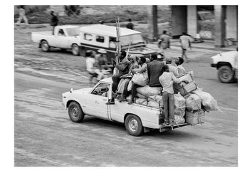 People, timber, grains and food goods cram into the tray of utility vehicle to return to mountain villages. Captured on Ilford HP5 black and white negative film. Kabale, Western Uganda.